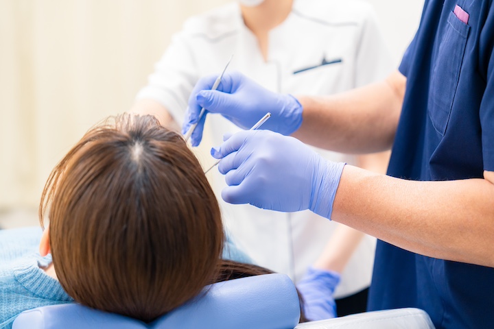 割れたセラミックの歯を歯科医師に治してもらっている女性