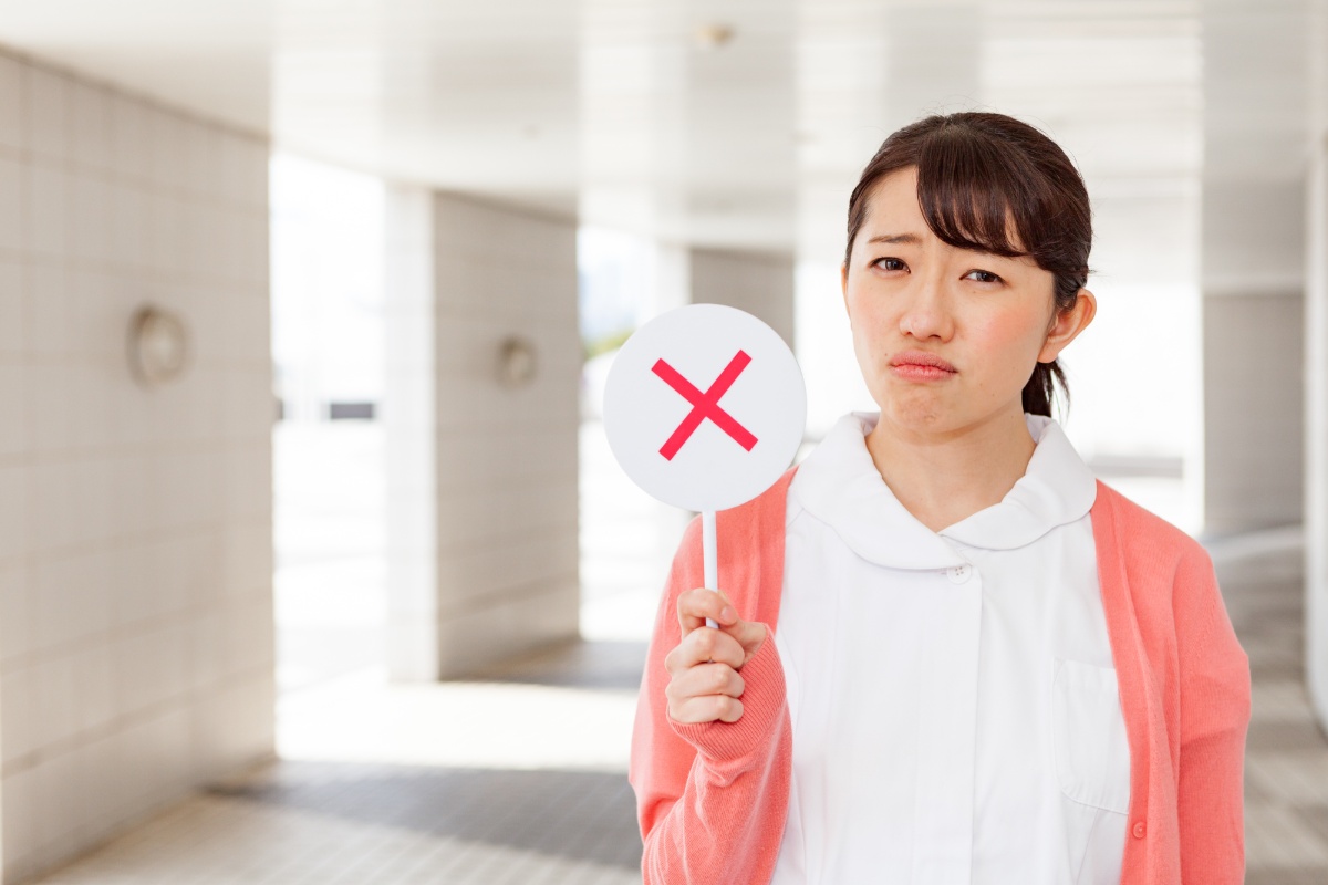 バツマークを掲げて残念がる女性